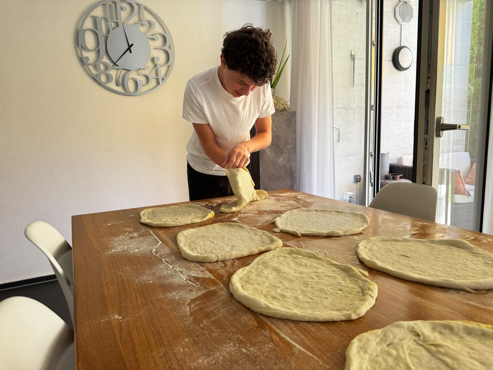 Von Hand gezogener Pizzateig auf einem bemehlten Holztisch