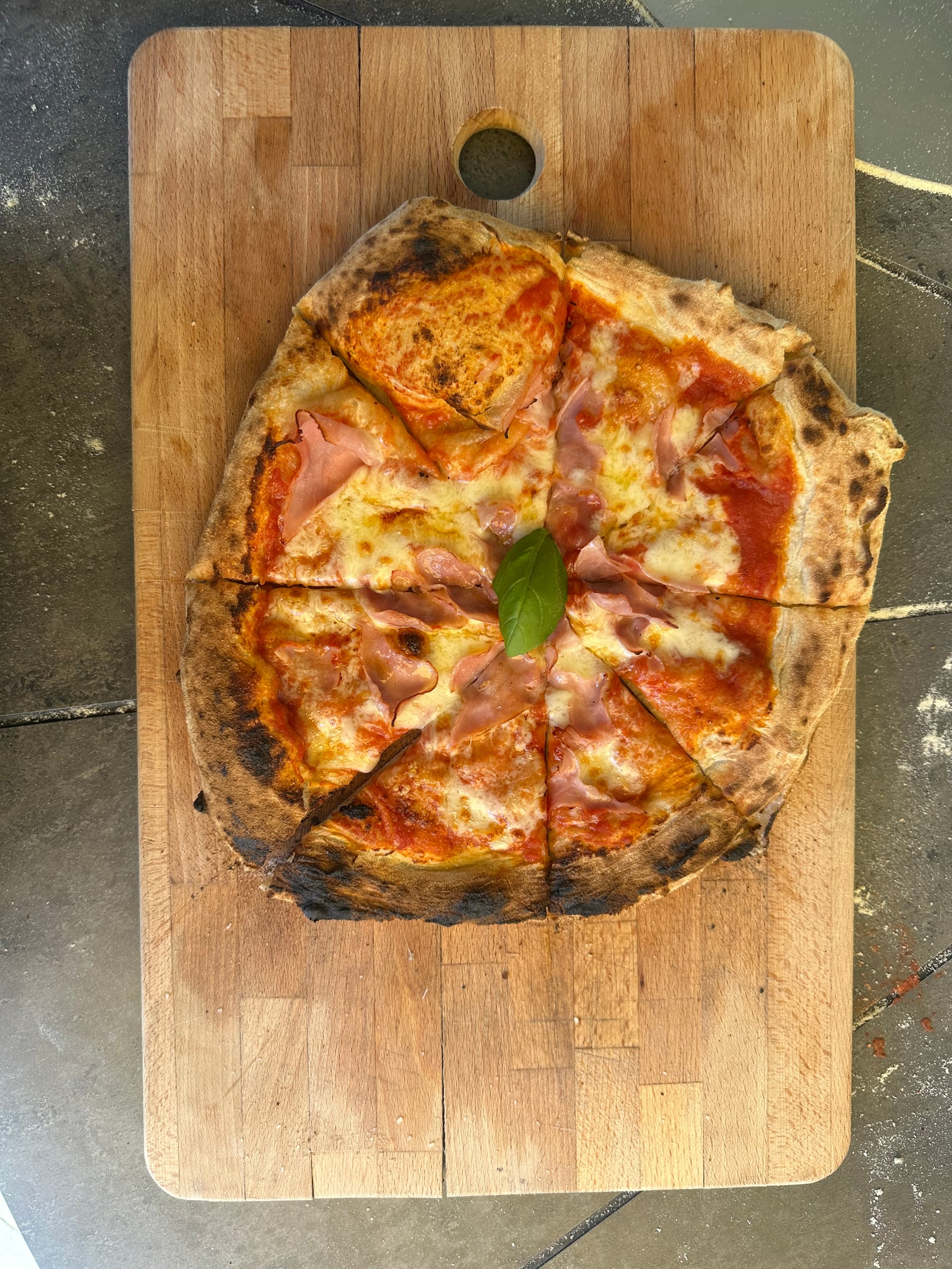 Eine frisch gebackene Pizza Guys Prosciutto auf einem Holzbrett
