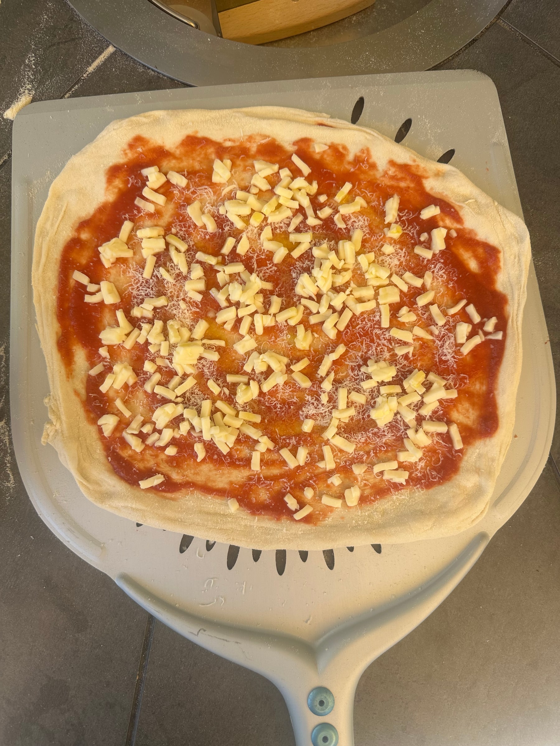 Eine Pizza Guys Pizza beim Belegen vor dem Backen